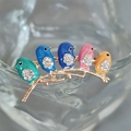Close-up of colorful enamel bird brooch with sparkling rhinestones on a golden branch - Pink Combo