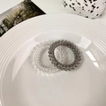 Detail of clear and dark grey spiral hair ties on a white ceramic plate decoration - Set of 2 / Transparent + Light Grey