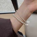 Detail shot of 4mm and 6mm white pearl elastic bracelets on model wrist for sizing comparison - 4+6mm Pearl Bracelet Set