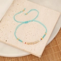 Himmelblaues geflochtenes Perlenarmband mit bunten Perlen auf Marmor- und Bambushintergrund - See Blau