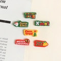 Macro view of six colorful resin Christmas themed charms including Santa and trees - Merry Christmas Banner Sign