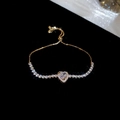 Detailed close-up of a heart-shaped zircon slider bracelet with gold finish - Gold-White Zirconia