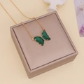 Detail of a green glass butterfly pendant on a gold chain displayed on a jewelry box - Green