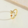 Macro shot of gold airplane ring with white zircon stones and a red gemstone accent - Cross Style