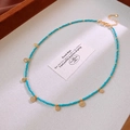 Détail du collier de perles bleu ciel avec sept pendentifs pièces d'or et fermoir mousqueton - Bleu
