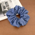 Indigo denim hair scrunchie with twill texture on a rustic wooden background - Solid Light Denim