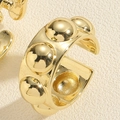 Macro-opname van vergulde oorbellen met bolvormige reliëftextuur en gepolijste glans - Ronde Stud Ring / Goud