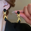 Vintage resin teardrop earrings with golden metal frames shown on a model and hand - Cross Black Water Drop Resin Style (7#)