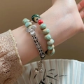 Gros plan d'un bracelet à double rangée avec perles vertes et pendentif fleur argenté - Style Multicouche de Perles en Céramique Fleur