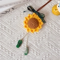Detail eines handgehäkelten Sonnenblumen-Anhängers mit Glücksbringern und Dekoband - Frieden und Freude Stil