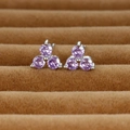 Macro detail of purple gemstone clover stud earrings set in silver metal on brown velvet - Silver/Purple Zirconia