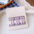 Detailed view of three cute purple bone-shaped hair clips on a white accessory display card - Purple