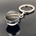 Macro detail of Jupiter glass dome keychain with polished silver metal ring on black surface - Jupiter