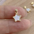 Star-shaped white mother of pearl pendant with gold metal frame held by hand - Gold White Shell