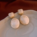 Detailed shot of retro oval earrings with marbled resin and gold-plated metal borders - Marble Pattern Beige Oval Drop / Silver Pin Gold Tone Cream White