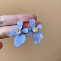 Detailopname van blauwe hars bloem oorbellen met marmeren textuur en glanzend zirkoon - Blauw