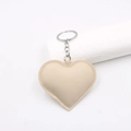 Detail of a beige heart-shaped faux leather keychain with silver metal ring and stitching - Off-white