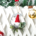 Close-up detail of festive Christmas gnome iron wreath with Welcome sign and greenery - Red Hat Gnome Door Hanging