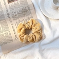 Elegant gold velvet scrunchie ponytail holder accessory on vintage newspaper background - Khaki