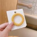 Elastico per capelli a spirale giallo su cartoncino con sfondo in legno caldo - 5cm / Giallo Zenzero