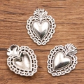 Three silver Sacred Heart metal pendants displayed on a textured wooden background - 27B2-2 Crown Sacred Heart