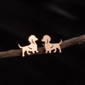 Macro detail of rose gold dachshund stud earrings on a natural wood branch - Sitting Dachshund (780) / Rose Gold