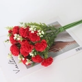 Bouquet d'œillets artificiels rouges avec feuilles vertes sur magazine pour décoration - Rouge