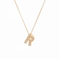 Macro shot of gold letter R pendant with micro-paved cubic zirconia on minimalist chain - Letter R