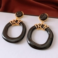 Close-up of vintage resin earrings with irregular hollow black rings and gold metal parts - Black Gold (925 Silver Needle)