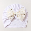 Detail of white infant turban featuring a decorative gold polka dot bow and soft fabric - White