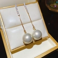 Dettaglio di orecchini pendenti dorati con cristalli brillanti e una perla bianca lucida - Oro (Perno in Argento S925)