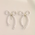 Elegant woven faux pearl bow earrings in a creamy white finish with silver studs - Silver