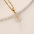 Macro shot of gold twist chain with a transparent resin cross pendant on white surface - Light Rose Quartz