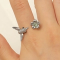 Detailed close-up of hummingbird and flower ring with green gemstone on finger - Hummingbird With Green Rhinestone Style (9632) / Antique Silver