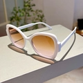 Detail view of white wide-frame sunglasses with orange gradient lenses on a grey surface - White Frame Tea Pink Lens