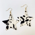 Détail macro de boucles d'oreilles en cuir en forme d'étoile avec motif vache et crochets dorés - Style Forme Étoile Imprimé Vache (6)