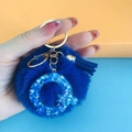 Close-up of blue pompom keychain with resin letter Q and heart glitter details - Letter Q