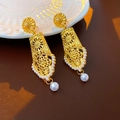 Close-up of golden hollow flower earrings with white pearl details on a white dish - Silver Pin - Matte Gold
