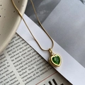 Primer plano del collar de corazón con gema verde y cadena de serpiente dorada - Verde