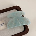 Close-up of light blue acetate hair claw with rhinestones on a wooden tray - Blue