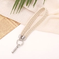 Detalle de la correa de muñeca de algodón trenzado beige con anillo de metal plateado - Blanco