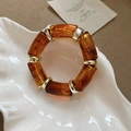 Close-up of amber acetate resin beads and gold metal spacers on an elastic bracelet - Brown