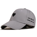 Close-up of grey baseball cap featuring heart embroidery and slogan love her but leave her wild - Gray