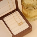 Close-up of gold stainless steel eye pendant in a premium wooden jewelry storage box - Pink
