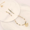 Macro detail of natural stone beaded necklace featuring an evil eye pendant and gold accents - Tree Agate