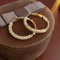 Macro view of gold-tone geometric hoop earrings with multi-row pavé set white crystals - Gold Double-Row Pave Rhinestone Hoop Earrings