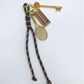 Vintage braided rope keychain with gold tennis racket and abacus charms on white background - Coffee