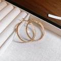 Macro shot of gold textured oval earrings with intricate woven pattern detail - Gold Irregular Wrinkle Texture Style