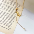 Detail der goldenen Schmetterlingskette mit Perlenanhänger auf Vintage-Hintergrund - Schmetterling