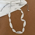 Detailed macro view of vintage silver leaf-shaped chain links with textured metal surface - Silver-Leaf Style